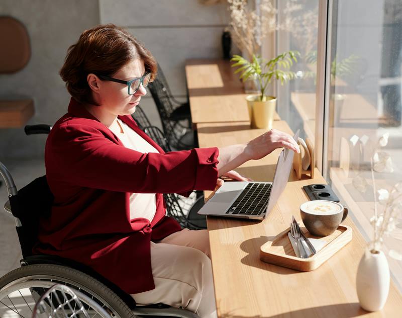 Professional woman in a wheelchair leading a team meeting in an office, representing inclusion and workplace advocacy.